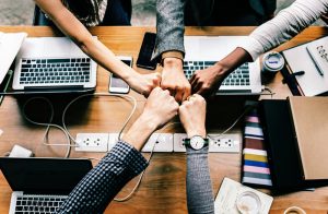 Five hands coming together over a table